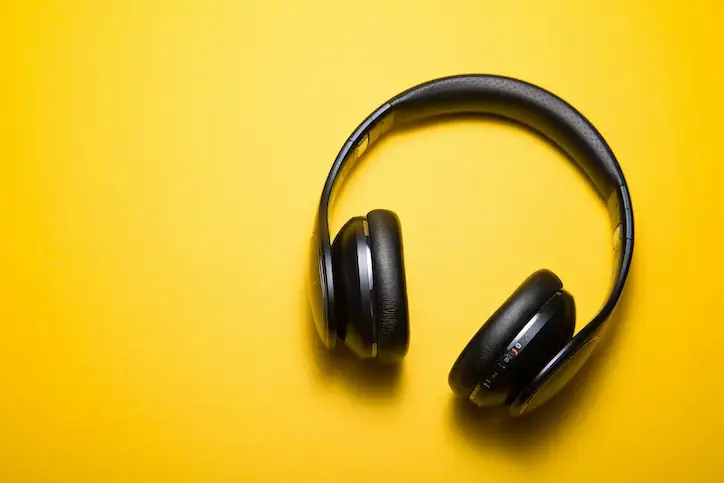 Black wireless headphones on vibrant yellow background